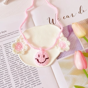 Close-up of handmade pink crochet pet collar with smiley face and flower charms