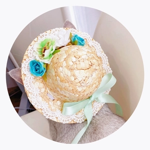 Detail of pet straw hat with white lace, floral decor and green ribbon for dogs and cats