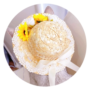 Detail of pet straw hat featuring white lace trim, sunflower and rose decorations