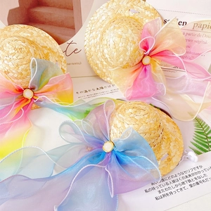 Detail of three mini straw hats for pets featuring oversized rainbow organza bows and pearls