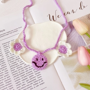 Detail of hand-crocheted purple pet collar with smiley face pendant and small flowers