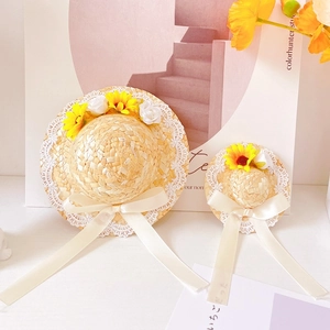 Detail of straw pet hat featuring white lace trim, sunflower, and white silk ribbons