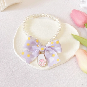Detail of pet necklace with white pearls, lavender bow and cat paw enamel pendant