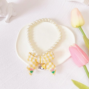 Detail showing pet pearl necklace with yellow checkered bow and cartoon cat pendant