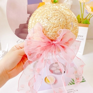 Macro detail of hand-woven straw pet sun hat with a large pink organza bow and floral pattern