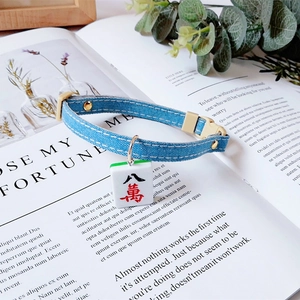 Detail of blue denim pet collar with adjustable buckle and 'Eight Wan' mahjong charm