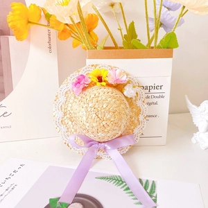 Macro shot of pet straw hat with colorful faux flowers, lace trim and purple ribbon
