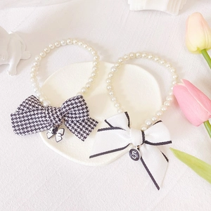 Detail of elegant faux pearl cat collar featuring houndstooth bow and numeric charm