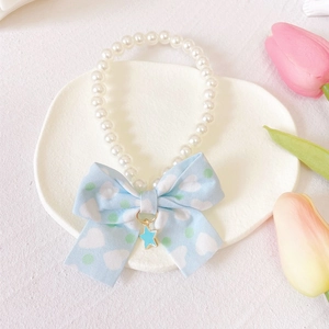 Detail of pet pearl collar with light blue bow and blue star pendant on white tray