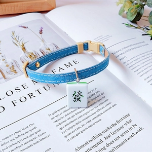 Blue denim pet collar detail with green Mahjong fortune pendant and adjustable buckle