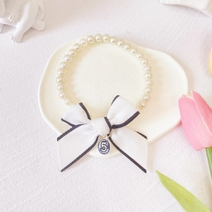 Close-up of pearl pet collar with houndstooth bow and enamel number 5 pendant