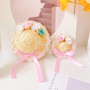 Detail of pet straw hats with lace edging, faux flowers, and pink satin bows