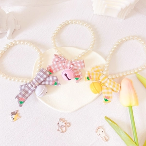 Macro detail of houndstooth pet collars with pearls, floral embroidery and bells