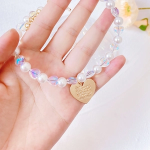 Detail of pet pearl necklace featuring heart-shaped charm and gold extension chain