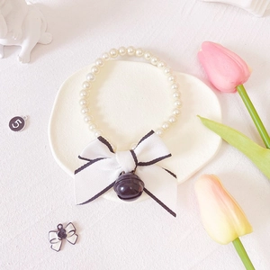 Detailed view of a white pearl pet collar featuring a white bow and a small hanging bell