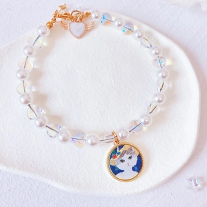 Detail of beaded pet necklace with white pearls, iridescent hearts and cat pendant