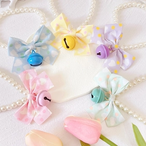 Close-up of pearl pet necklaces with colorful heart-print bows and matching bells