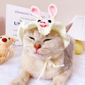 Close-up of a white handmade knitted rabbit hat for cats with pink ears and tie straps