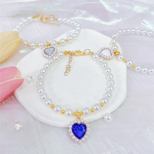 Detailed macro view of heart pendants with sapphire blue and white stones on pearl pet collars