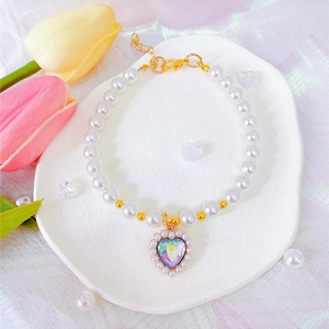 Detail of a pearl cat collar with a heart-shaped gemstone pendant and adjustable gold chain