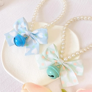 Detailed view of pearl pet collars with decorative fabric bows and colored bells
