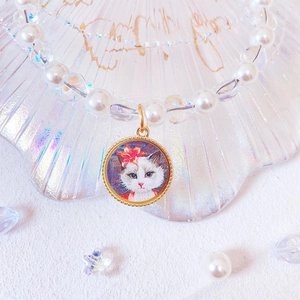 Detail of white pearls and iridescent beads with a floral cat pendant in a shell tray