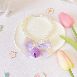 Detail of pet pearl necklace with a purple polka dot bow and a matching bell charm