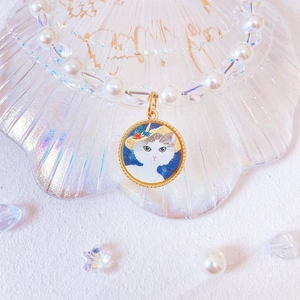 Detail of handmade pet pearl necklace featuring a cat pendant in a shell tray