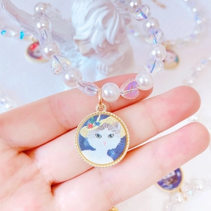 Macro shot of pearl pet necklace featuring a round gold-rimmed white cat avatar pendant