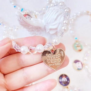 Close-up of handmade pet pearl necklace with gold heart pendant and star beads