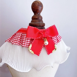 Detail of red checkered pet collar with ribbon bow, pearl pendant and mesh frill