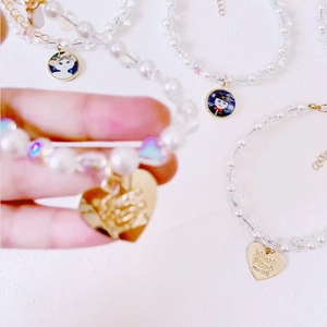Macro detail of handmade pet pearl necklace with heart and cat pendants and metal clasp