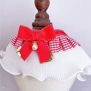Close-up of pet collar with red bow, white pleats, and elegant pearl pendant detail
