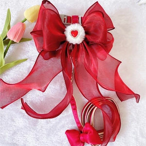 Detail of red organza pet harness featuring a large bow with heart and fur ball accent