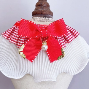 Detail of red bow pet collar with lace frills, faux pearl pendant and gold trim details