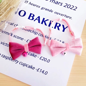 Detail of pink velvet pet collars with bows and heart pattern bells for cats and dogs