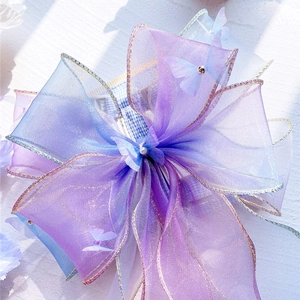 Close-up of a gradient purple organza pet harness bow with butterfly and pearl accents