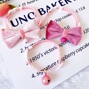 Detailed view of pink velvet pet collars with bows, bells and adjustable buckles