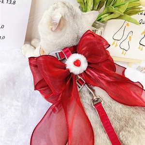 Detail of red cat harness with large organza bow, plush ball, and heart gem ornament