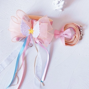 Detail eines rosa Katzengeschirrs mit Netzschleife, Engelsflügeln und karierter Leine