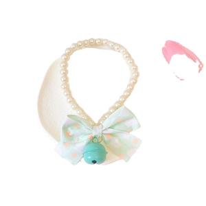 Cat pearl necklace with mint green polka dot bow and metal bell on a round tray
