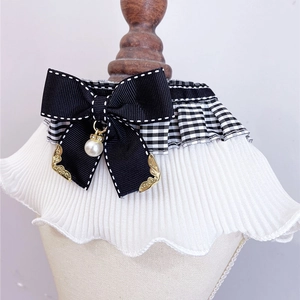 Detail of pet lace collar with plaid ruffles, black bow and pearl pendant on model