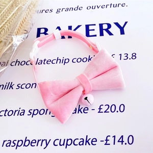Detail of pink velvet pet collar featuring a cute bell and adjustable white buckle