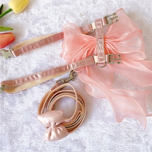 Detail of pink pet harness with organza bow and satin leash on white plush rug