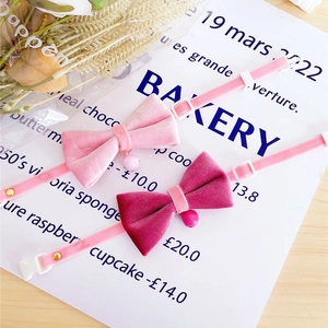 Close-up of pink velvet pet collars with bow ties and bells on white background