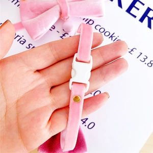 Detailed close-up of pink velvet pet collar with white safety buckle and gold rivet