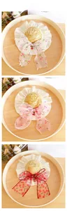 Detail view of woven pet straw hats with cherry bowknots in white, pink and red colors