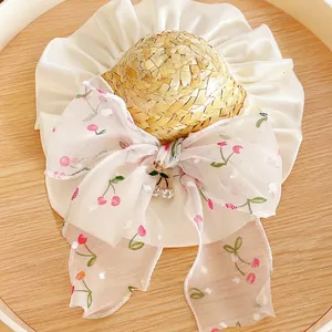 Pet straw hat with white ruffle trim and a pink cherry pattern bow for cats and dogs