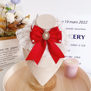 Elegant red bow pet collar with white lace and pearl accents on a display stand