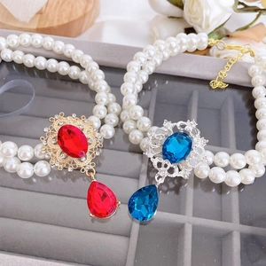 Detailed macro view of double-layer pearl pet necklaces with red and blue gemstones